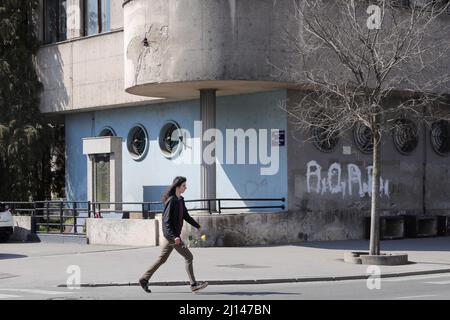 (220322) -- BELGRADE, le 22 mars 2022 (Xinhua) -- Un homme avec une fleur à la main passe le bâtiment de commandement bombardé de l'armée de l'air yougoslave à Belgrade, Serbie, le 21 mars 2022. À Belgrade, il y a beaucoup de cicatrices laissées par les bombardements de l'OTAN. Les bombardements de l'OTAN en Yougoslavie ont commencé le 24 mars 1999. Au cours de l'attaque militaire de 78 jours, 2 500 civils ont été tués et environ 25 000 objets ont été endommagés, dont des aéroports, des hôpitaux, des écoles, des monuments culturels et des infrastructures routières, selon le gouvernement serbe. (Xinhua/Zheng Huansong) Banque D'Images