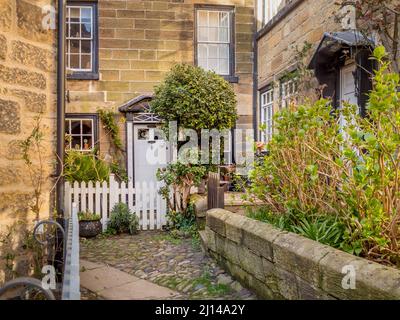 Maison traditionnelle en pierre avec clôture de piquetage blanche, située dans une ruelle étroite dans la vieille ville de Robin Hoods Bay, dans le North Yorkshire. Banque D'Images