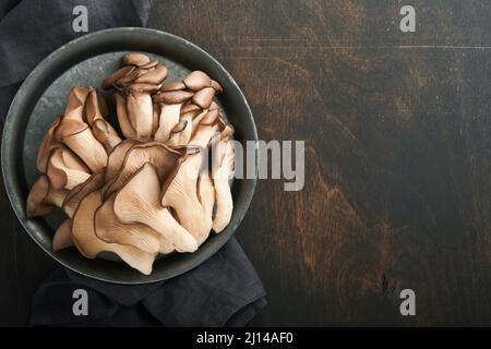 Champignons d'huîtres frais. Repassez le vieux bol de délicieux champignons bio sur fond de bois, vue de dessus avec espace pour le texte. Banque D'Images