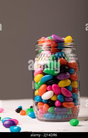 Gros plan de bonbons multicolores dans des pots en verre sur fond gris avec espace de copie Banque D'Images