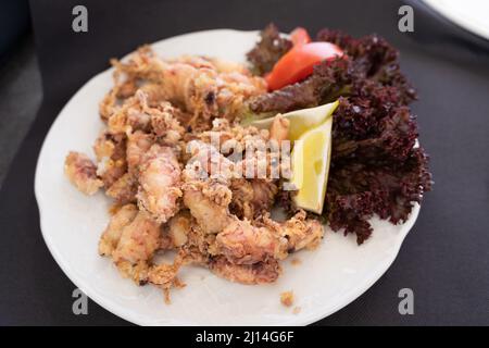 Les petits squidés frits sur l'assiette avec du citron, de la laitue et de la tomate. Tapa traditionnel de fruits de mer espagnols Banque D'Images