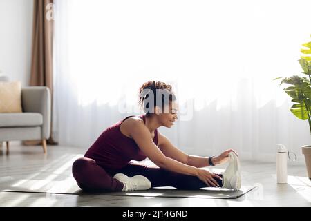 Femme afro-américaine active qui s'étire à la maison Banque D'Images
