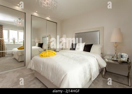 Chambre dans la maison moderne, armoires à miroirs, couvre-lit blanc, chambre lumineuse spacieuse, Banque D'Images