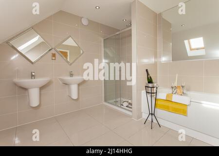 Champagne à côté de la baignoire dans une salle de bains moderne avec toilettes, cabine de douche, lavabos, lavabos, lavabos, carrelage. Banque D'Images
