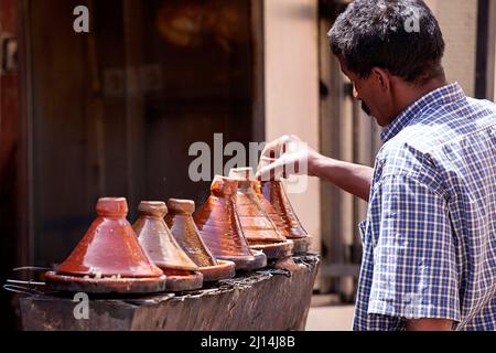 Des hommes marocains locaux préparent le déjeuner dans un tagine marocain traditionnel, au Maroc Banque D'Images