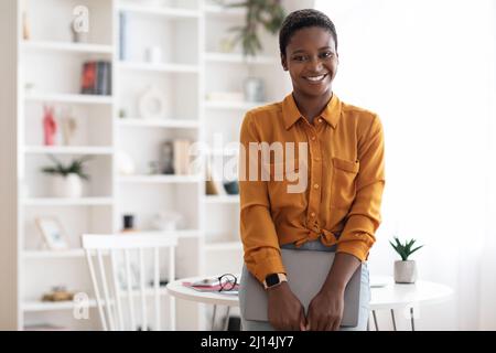 Jolie femme afro-américaine posant avec un ordinateur portable au bureau Banque D'Images