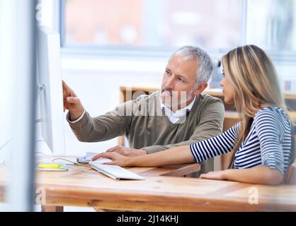 Deux têtes sont meilleures qu'une. Cliché d'une discussion entre deux collègues sur un poste de travail. Banque D'Images