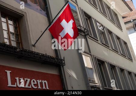 Lucerne, Suisse, le 10 mars 2022 le drapeau suisse est suspendu sur la façade d'un ancien bâtiment de la vieille ville Banque D'Images