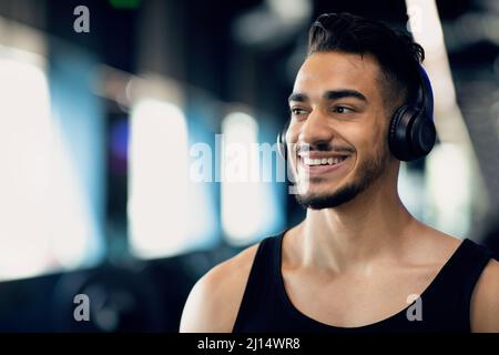 Gros plan Portrait d'un homme beau souriant du Moyen-Orient portant un casque sans fil Banque D'Images