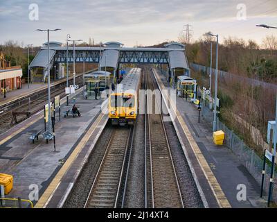 Voies et plates-formes ferroviaires à la gare de Hooton à Wirral, dans le nord-ouest de l'Angleterre, Royaume-Uni. Un seul train de banlieue attend à la plate-forme pour les navetteurs à ali Banque D'Images