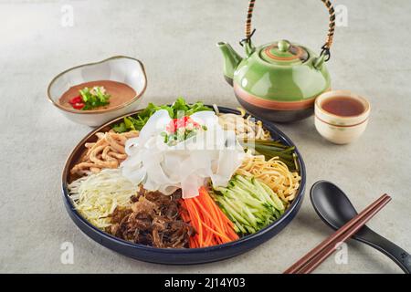 Haricots mung nouilles plates au sauce au sésame servies dans un plat avec des baguettes vue latérale sur fond gris Banque D'Images