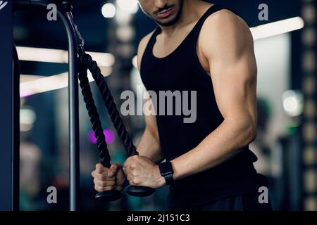 Concept de culturisme. Jeune homme musclé travaillant des biceps sur la machine de fitness Banque D'Images