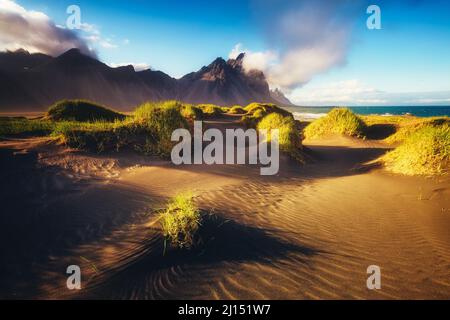 Belle vue sur les collines jaunes illuminées par la lumière du soleil. Scène majestueuse et magnifique. Emplacement célèbre place Stokksnes cape, Vestahorn (montagne Batman Banque D'Images