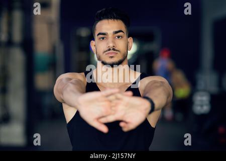 Portrait de Sporty Young Arab Man Stretching Arms à Camera Banque D'Images