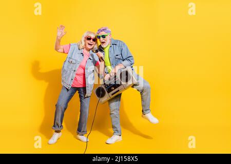 Photo de charmante petite amie douce garnie de denim tenue à l'écoute boîte à perche chantant isolé couleur jaune arrière-plan Banque D'Images