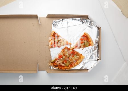 Le reste de la pizza est dans la boîte. Vider la boîte à pizza avec trois tranches de reste. Vue de dessus Banque D'Images