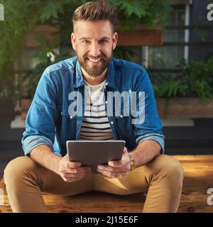 Je ne peux pas survivre sans les médias sociaux à mes côtés. Portrait d'un beau jeune homme à l'aide d'une tablette numérique. Banque D'Images