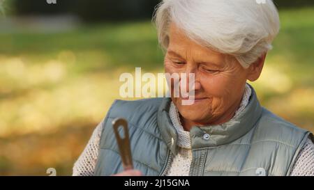 Portrait d'une femme caucasienne d'âge souriant ayant un repas regardant vers le bas parc arrière-plan moyen gros plan focus sélectif espace de copie . Photo de haute qualité Banque D'Images