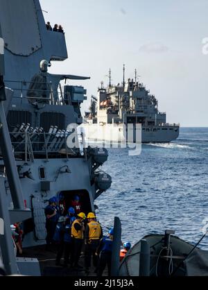 MER DE CHINE ORIENTALE (16 mars 2022) le destroyer à missiles guidés de la classe Arleigh Burke USS Ralph Johnson (DDG 114) tire à côté du navire à cargaison sèche de la classe Lewis et Clark USNS Matthew Perry (T-AKE-9) en vue d'un réapprovisionnement en mer. Ralph Johnson est affecté à la Force opérationnelle 71/Escadrier Squadron (DESRON) 15, la plus importante force de surface déployée à l’avant de la Marine et la principale force de surface de la flotte américaine 7th. (É.-U. Photo de la marine par le spécialiste des communications de masse 2nd classe Samantha Oblander) Banque D'Images