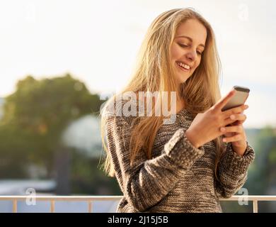 Découvrez le dernier buzz sur les réseaux sociaux. Photo courte d'une jeune femme attirante qui envoie des SMS sur son téléphone portable à l'extérieur. Banque D'Images