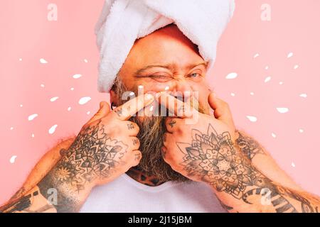 Un homme avec une barbe et une serviette au-dessus de la tête tire un bouton Banque D'Images