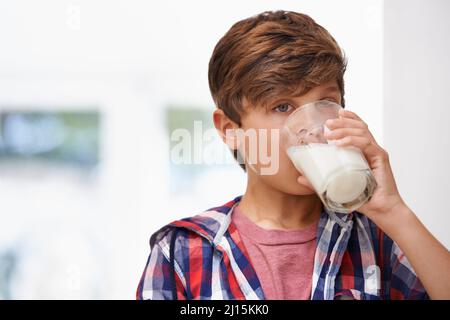 Ah... délicieux. Un jeune garçon boit un verre de lait. Banque D'Images