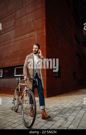 Jeune homme avec vélo allant au travail. Appel avec le responsable. Homme d'affaires créatif dans un espace affaires moderne. Banque D'Images