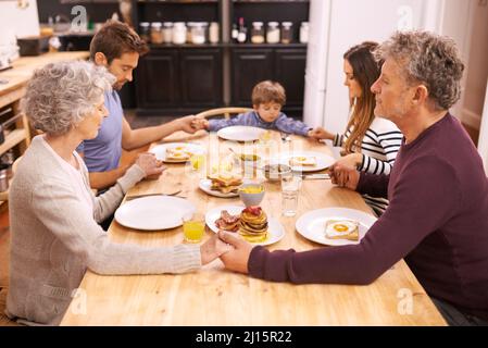 Bénir cette nourriture à nos corps. Une photo de famille en train de dire grâce avant de prendre le petit déjeuner. Banque D'Images