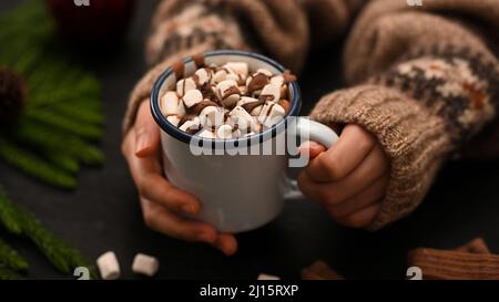 Gros plan, Un délicieux chocolat chaud fondu avec une petite tasse de guimauves dans la main d'une femme. Concept des boissons d'hiver Banque D'Images