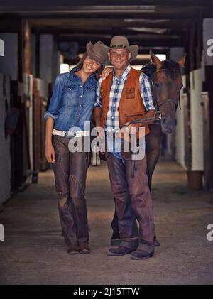 La vie au ranch. Photo d'un cowboy et d'une cowgirl qui mènent un cheval hors d'une écurie. Banque D'Images