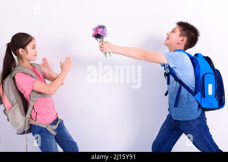 Un garçon excité donne à une fille un bouquet de fleurs Banque D'Images