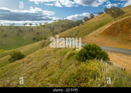 Route de campagne australienne sinueuse à travers une colline verdoyante et sèche Banque D'Images