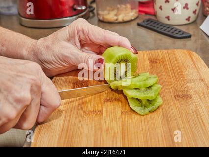 Le chef prépare une tarte aux kiwis, coupez les kiwis en tranches Banque D'Images