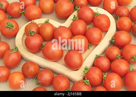 Fond de tomates cerises - dans une plaque de coeur en bois - avantages de tomates concept Banque D'Images