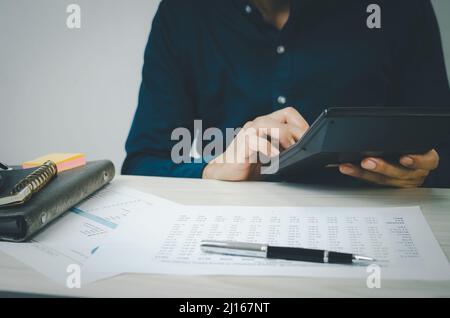 Mains de hommes tenant calculatrice et documents papier .concepts de la fiscalité et de l'investissement dans le financement économique des affaires. Banque D'Images
