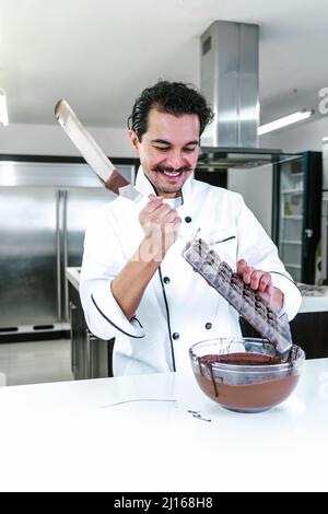 Jeune latiman chocolatier en chapeau de chef, avec bonbons mexicains au chocolat sur une assiette dans une cuisine commerciale au Mexique Amérique latine Banque D'Images