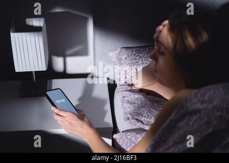 Troubles du sommeil et insomnie. Femme sans sommeil regardant le temps de l'horloge du téléphone la nuit. Ne pas s'endormir, désordre. Anxiété, stress et dépression. Banque D'Images