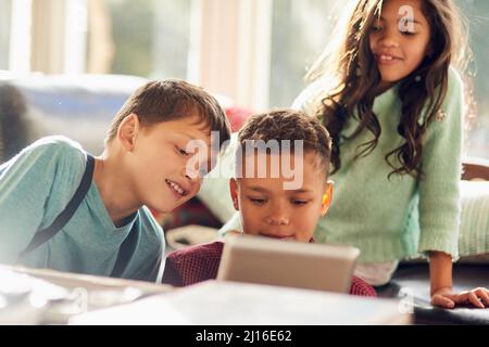 Les enfants sont occupés grâce à la technologie. Prise de vue de jeunes enfants à l'aide d'une tablette numérique à la maison. Banque D'Images