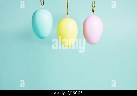 Arrière-plan de Pâques. Une collection d'oeufs de Pâques dans des couleurs pastel accrochés sur un fond bleu-vert. Concept de Pâques Banque D'Images
