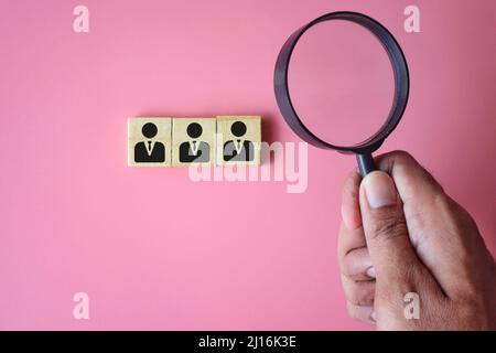 Concept de recrutement, d'emploi et d'embauche. Main tenant la loupe et les cubes en bois avec l'icône personne. Banque D'Images