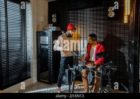Des hommes jouant des tambours électriques dans un studio à domicile Banque D'Images