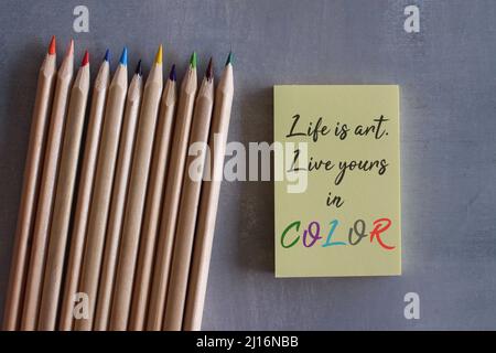 Crayons de couleur et papier-notes jaune avec des citations LA VIE EST ART. VIVEZ LA VÔTRE EN COULEUR. Citations motivationnelles Banque D'Images