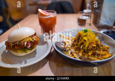 Petit Bao délicieux hamburger au poulet en gros plan, frites maison avec sauce aux truffes et laitue jaune, thé glacé frais. Petit pain blanc avec sauce chinoise. Banque D'Images