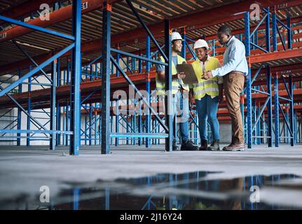 Ils ne se contentent pas de concevoir l'avenir, ils l'améliorent. Photo d'un groupe de constructeurs inspectant un chantier de construction. Banque D'Images