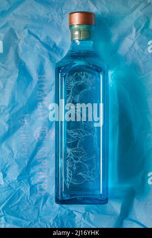 Bouteille de Bombay Sapphire Premier cru distillé London Dry Gin Vapor infusé au citron Murcian à la main sélection de plantes exotiques sur papier de soie bleu Banque D'Images