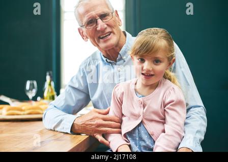 La plus ancienne et la plus jeune de la famille. Portrait d'un vieil homme joyeux et de sa petite fille jouant autour d'une tablette numérique à côté d'une Banque D'Images