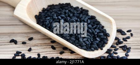 Graines de cumin noir de Nigella et cuillère sur le dos en bois de gros plan Banque D'Images