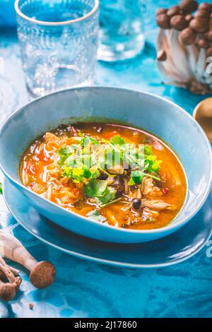 Curry rouge de poulet thaïlandais. Soupe traditionnelle thaïlandaise au curry rouge avec poulet, champignons et lait de coco sur fond bleu Banque D'Images