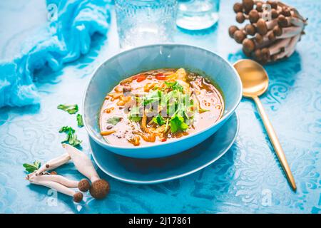 Curry rouge de poulet thaïlandais. Soupe traditionnelle thaïlandaise au curry rouge avec poulet, champignons et lait de coco sur fond bleu Banque D'Images