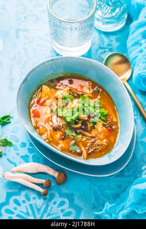 Curry rouge de poulet thaïlandais. Soupe traditionnelle thaïlandaise au curry rouge avec poulet, champignons et lait de coco sur fond bleu Banque D'Images